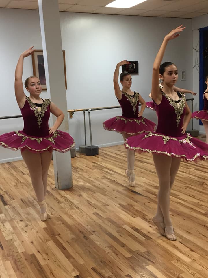 Three young ballerinas in a class at the dance studio.