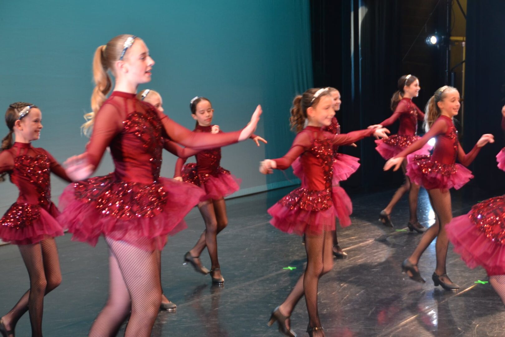 A group of young girls in red dresses dancing.