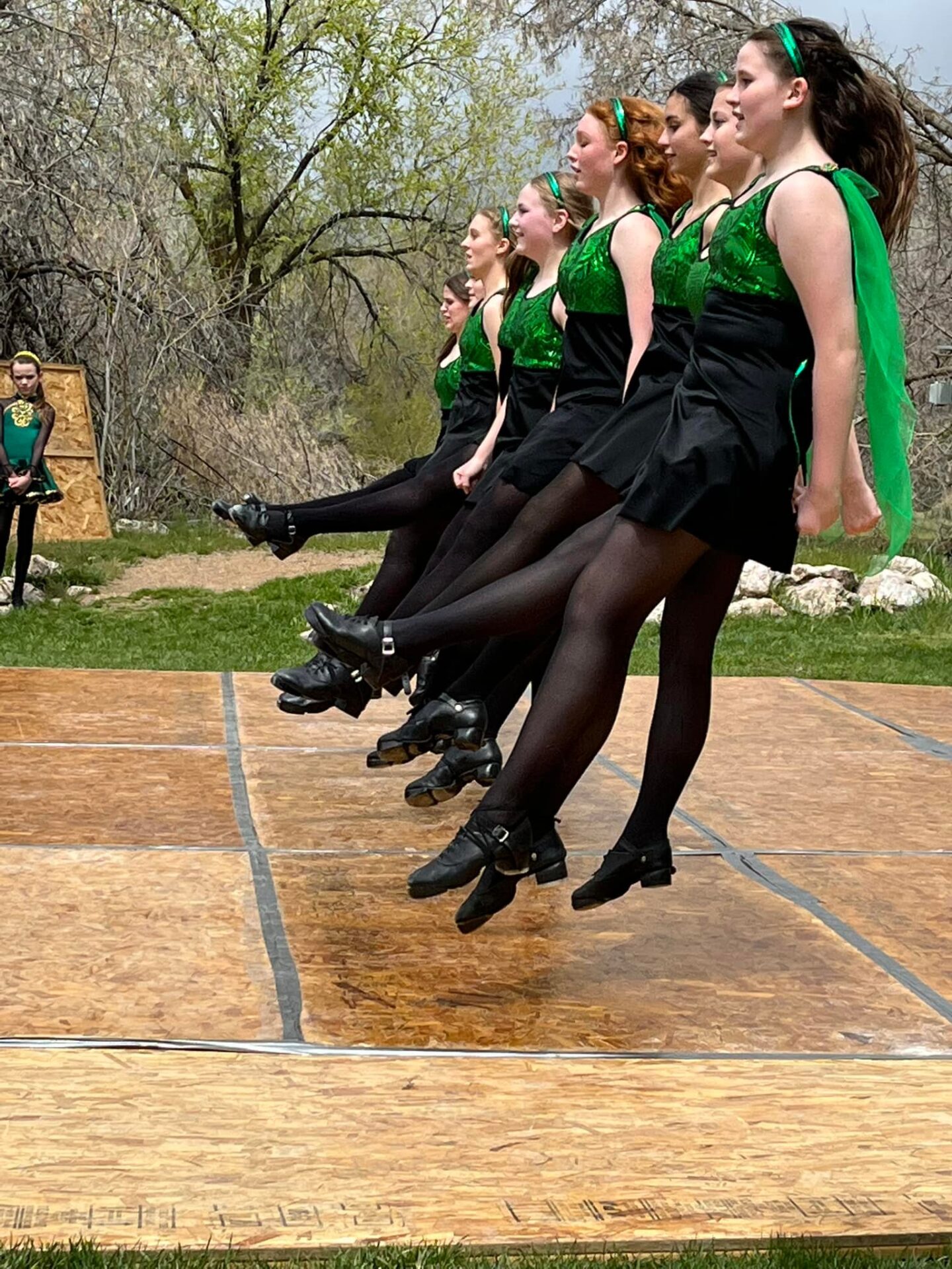 A group of women in green and black outfits doing a dance.